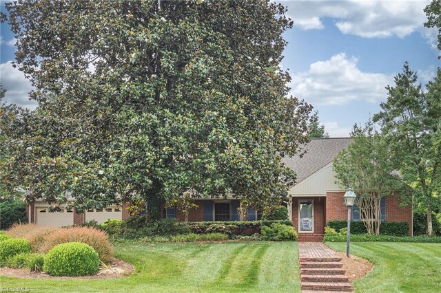 view of property hidden behind natural elements with a front lawn and a garage