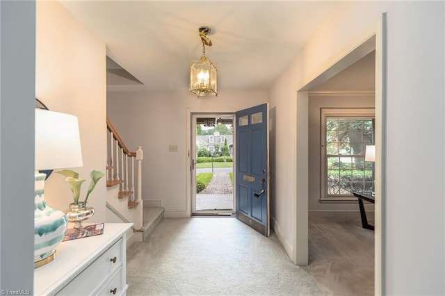 carpeted entryway with plenty of natural light and a chandelier