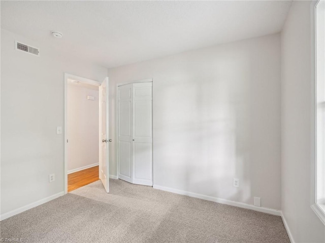 empty room with light colored carpet, baseboards, and a smoke detector