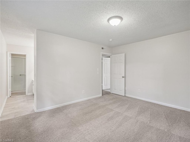 carpeted empty room with a textured ceiling and baseboards