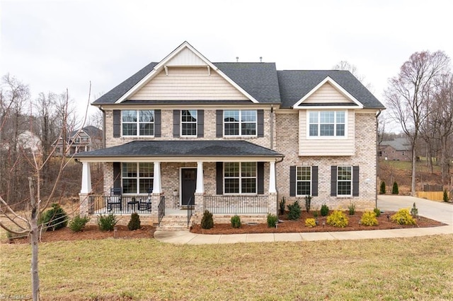 craftsman house featuring a porch, brick siding, and a front lawn