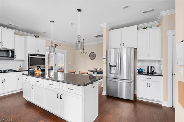 kitchen featuring hanging light fixtures, appliances with stainless steel finishes, a kitchen island, and white cabinets