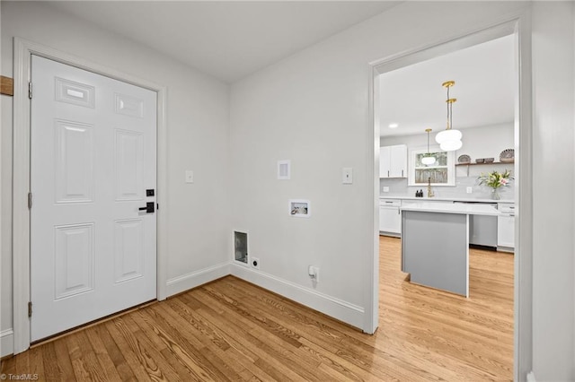 laundry room with baseboards, laundry area, a sink, washer hookup, and light wood-type flooring