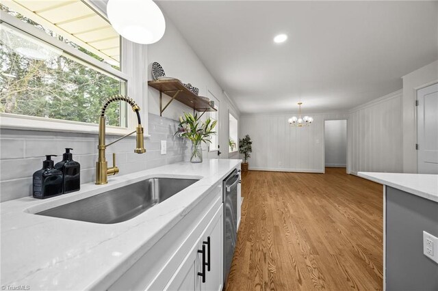 kitchen featuring open shelves, light wood-style flooring, a sink, backsplash, and a chandelier