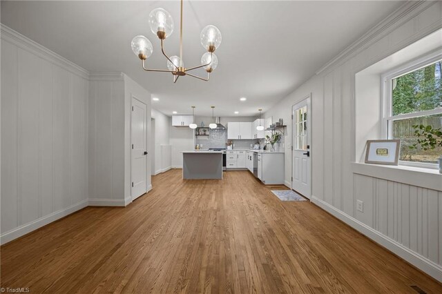 interior space featuring wood finished floors, an inviting chandelier, electric range, decorative backsplash, and light countertops