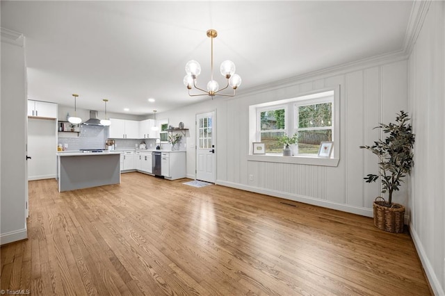 kitchen featuring light wood finished floors, dishwasher, wall chimney exhaust hood, and light countertops