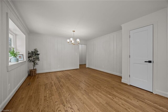 unfurnished room with baseboards, light wood-style floors, an inviting chandelier, and crown molding