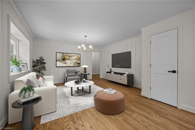 living area featuring baseboards, an inviting chandelier, wood finished floors, and crown molding