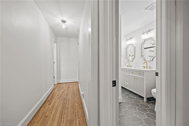 corridor featuring baseboards and a sink