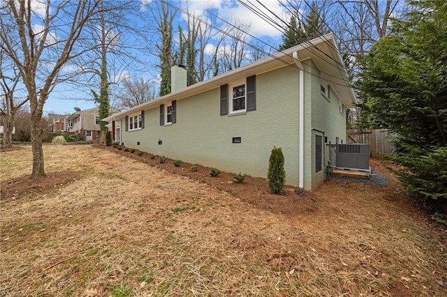 view of property exterior with brick siding, central AC unit, a chimney, crawl space, and an attached garage