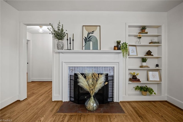 room details with built in features, baseboards, a brick fireplace, and wood finished floors