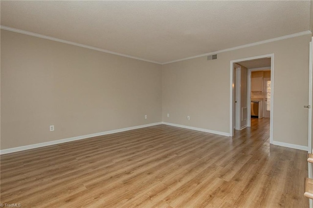 spare room featuring light hardwood / wood-style flooring, a textured ceiling, and ornamental molding