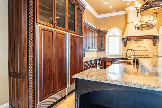 kitchen featuring sink, light stone counters, decorative light fixtures, light tile patterned floors, and ornamental molding