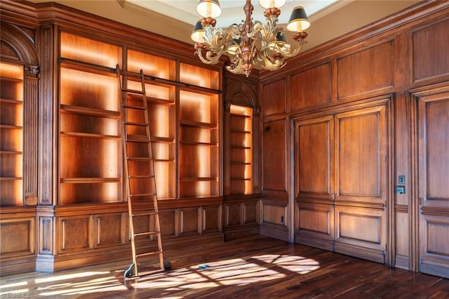 unfurnished office with ornamental molding, a barn door, dark wood-type flooring, an inviting chandelier, and built in shelves