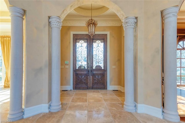 entrance foyer with ornamental molding, a chandelier, and french doors