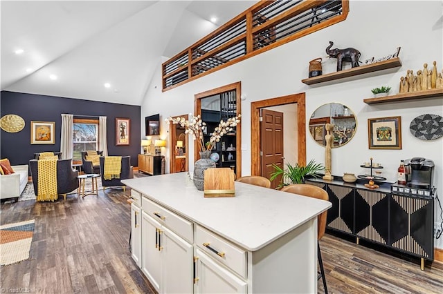 kitchen with a center island, high vaulted ceiling, a kitchen breakfast bar, dark hardwood / wood-style floors, and white cabinets