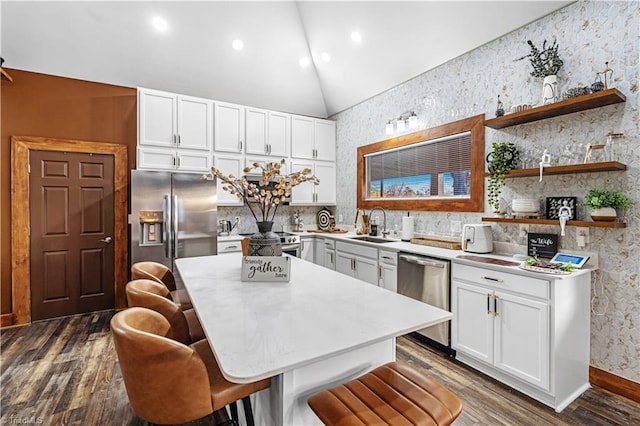 kitchen featuring a breakfast bar, sink, appliances with stainless steel finishes, a kitchen island, and white cabinets