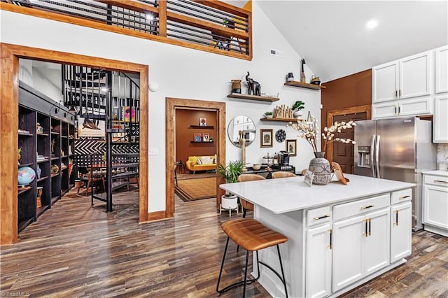 kitchen featuring high vaulted ceiling, a center island, white cabinets, a kitchen bar, and dark hardwood / wood-style flooring