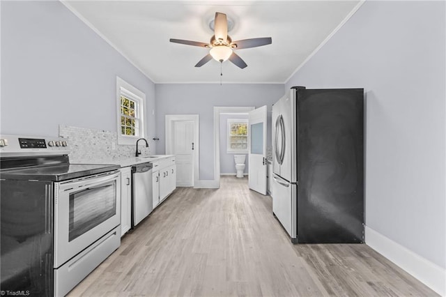 kitchen featuring sink, crown molding, light hardwood / wood-style floors, white cabinets, and appliances with stainless steel finishes