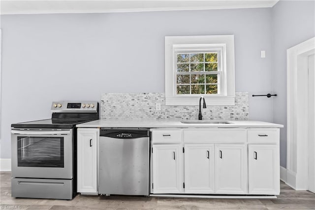 kitchen featuring backsplash, white cabinets, sink, light wood-type flooring, and stainless steel appliances