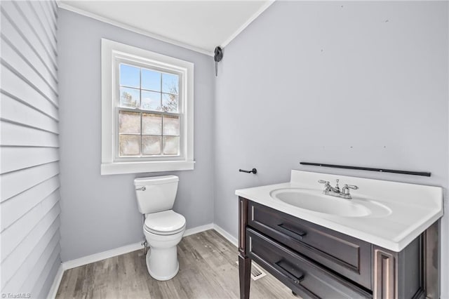 bathroom featuring toilet, vanity, ornamental molding, and hardwood / wood-style flooring