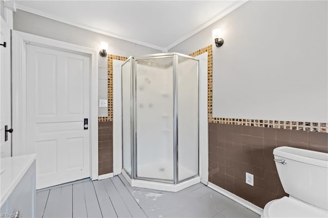 bathroom featuring ornamental molding, toilet, tile walls, and a shower with shower door