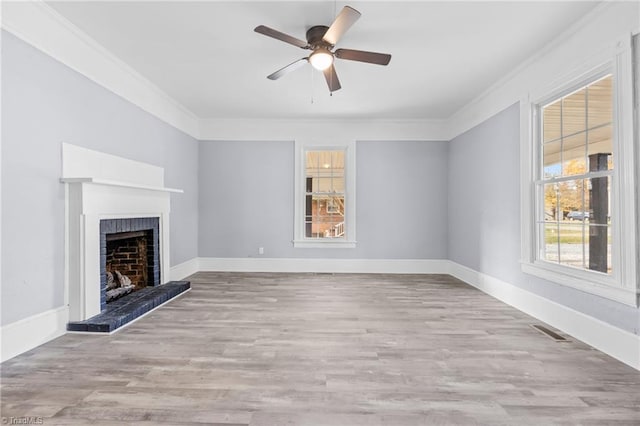 unfurnished living room featuring ceiling fan, light hardwood / wood-style flooring, ornamental molding, and a brick fireplace