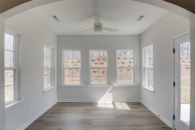 unfurnished sunroom with arched walkways, visible vents, and ceiling fan