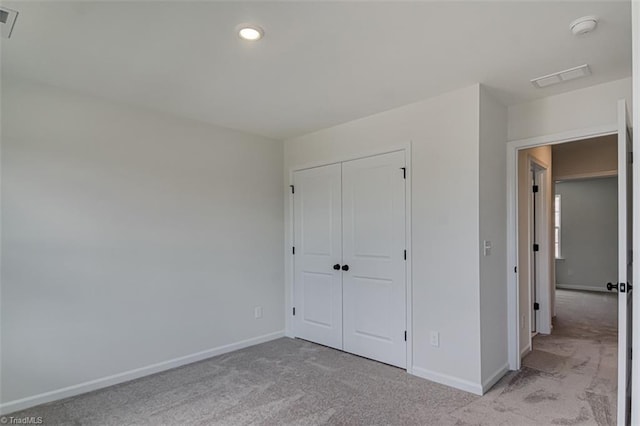 unfurnished bedroom featuring a closet, light colored carpet, visible vents, and baseboards