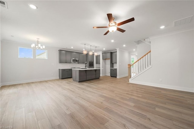 unfurnished living room featuring light wood-type flooring, crown molding, ceiling fan with notable chandelier, and sink