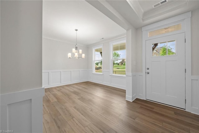 foyer with a notable chandelier, ornamental molding, and hardwood / wood-style floors