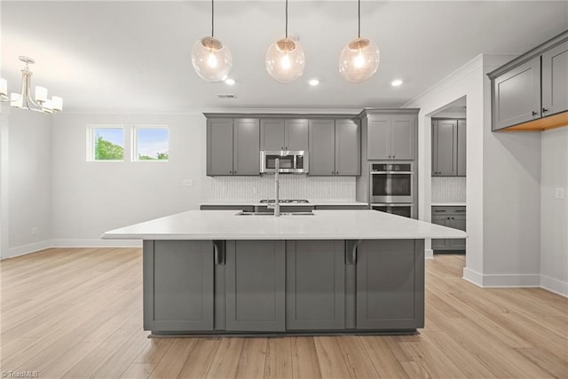 kitchen with appliances with stainless steel finishes, tasteful backsplash, decorative light fixtures, and gray cabinets