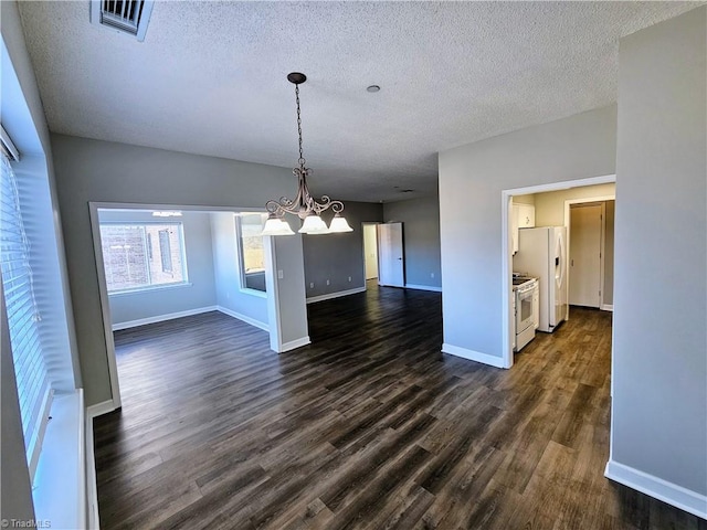 unfurnished dining area with dark hardwood / wood-style flooring, a textured ceiling, and an inviting chandelier