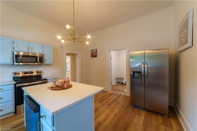 301 S Shaver St, Salisbury, NC 28144 - kitchen with appliances with stainless steel finishes, blue cabinetry, a chandelier, light countertops, and light wood finished floors