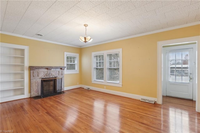1146 Rogers Rd, Graham, NC 27253 - unfurnished living room featuring light wood-type flooring, built in shelves, ornamental molding, a fireplace with flush hearth, and a chandelier