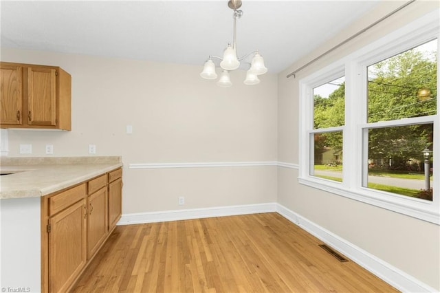 225 Harper St, Winston-Salem, NC 27104 - kitchen featuring light wood finished floors, light countertops, a chandelier, and pendant lighting