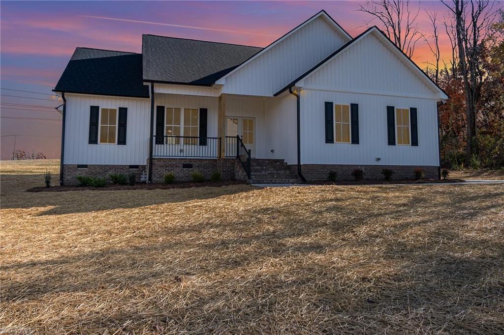 modern farmhouse style home with a yard and covered porch