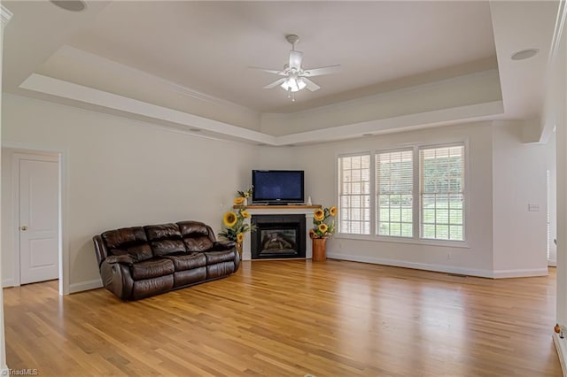 160 Serenity Pointe Dr, Kernersville, NC 27284 - living room featuring a raised ceiling, light wood-style flooring, ceiling fan, a glass covered fireplace, and crown molding