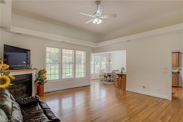 160 Serenity Pointe Dr, Kernersville, NC 27284 - living area with light wood-type flooring, a raised ceiling, a tiled fireplace, a ceiling fan, and ornamental molding