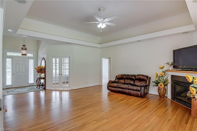 160 Serenity Pointe Dr, Kernersville, NC 27284 - living room with a tray ceiling, light wood finished floors, ceiling fan, a glass covered fireplace, and crown molding