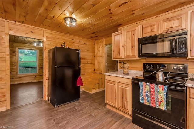 kitchen with wooden walls, black appliances, wooden ceiling, light brown cabinetry, and dark hardwood / wood-style flooring