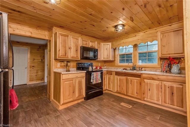 kitchen with black appliances, wooden walls, dark hardwood / wood-style floors, and sink