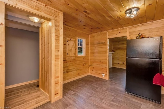 kitchen with wood walls, wood ceiling, hardwood / wood-style floors, and black refrigerator