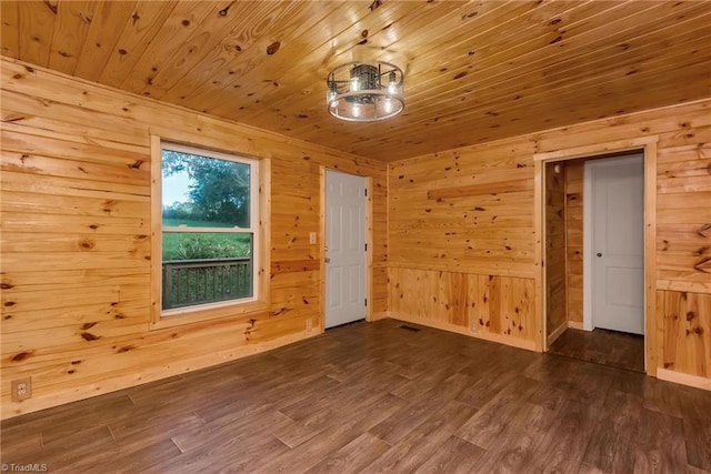 spare room featuring wood walls, wooden ceiling, and dark wood-type flooring