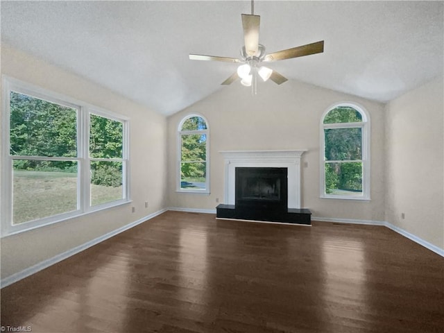 unfurnished living room featuring ceiling fan, dark hardwood / wood-style floors, vaulted ceiling, and a wealth of natural light