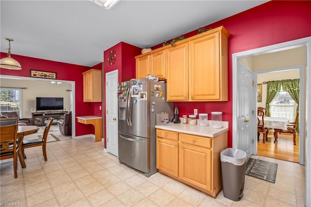 kitchen featuring pendant lighting, plenty of natural light, and stainless steel fridge with ice dispenser