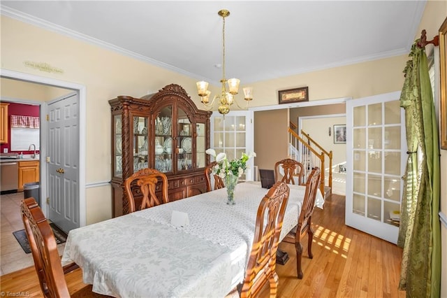 dining space featuring ornamental molding, sink, a chandelier, and light hardwood / wood-style flooring