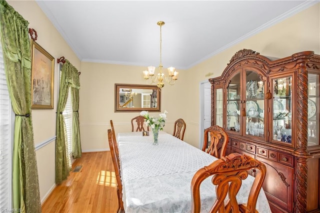 dining room featuring ornamental molding, a chandelier, and light hardwood / wood-style floors