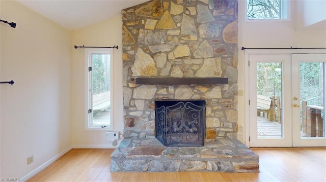 living room featuring hardwood / wood-style floors, lofted ceiling, french doors, and a fireplace