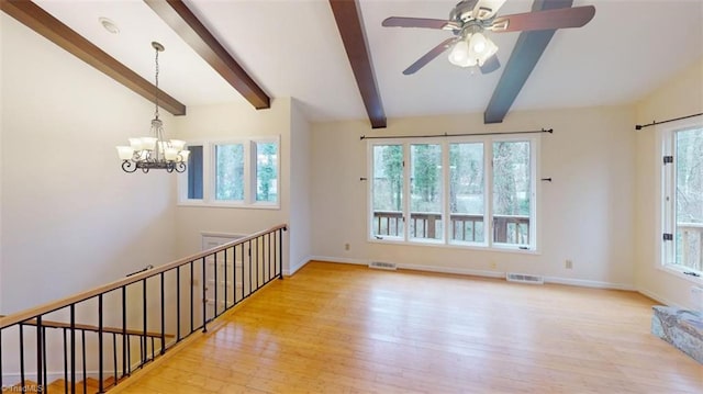 empty room with ceiling fan with notable chandelier, a wealth of natural light, and light wood-type flooring